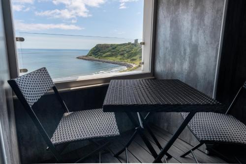 a table and chairs on a balcony with a view of the ocean at The Boat House Luxury Apartments Scarborough in Scarborough