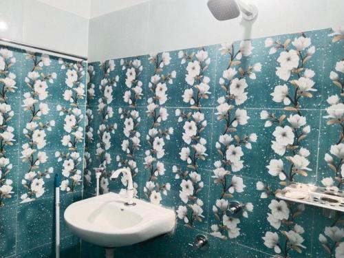 a bathroom with a wall covered in flowers on the wall at Bhanu Homestay in Nowgong