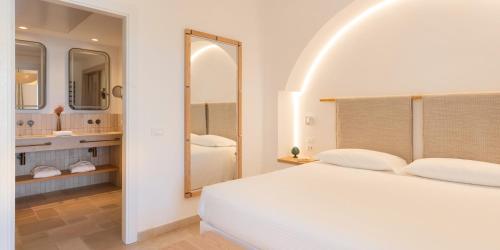a white bedroom with a large bed and a bathroom at Ostuni a Mare in Ostuni