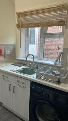 a kitchen with a sink and a washing machine at Town Centre House Sleeps 8 with parking in Stafford
