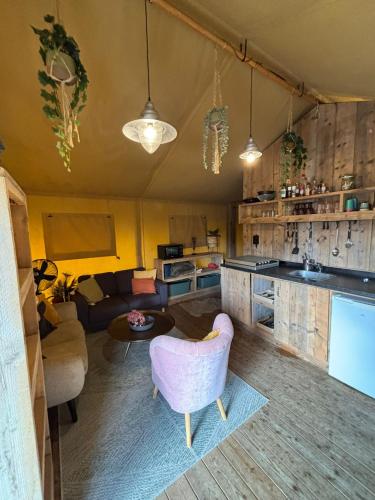 a kitchen and living room with a couch and a table at Luxe safaritent op watersportcamping in Grou