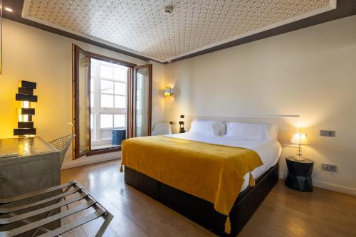 a bedroom with a large bed with a yellow blanket at Casas Reais Boutique in Santiago de Compostela