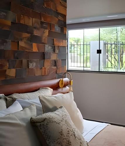 a bedroom with a brick wall and a bed with pillows at Studio Hebron: Refúgio Entre a Cidade e a Natureza in Anápolis