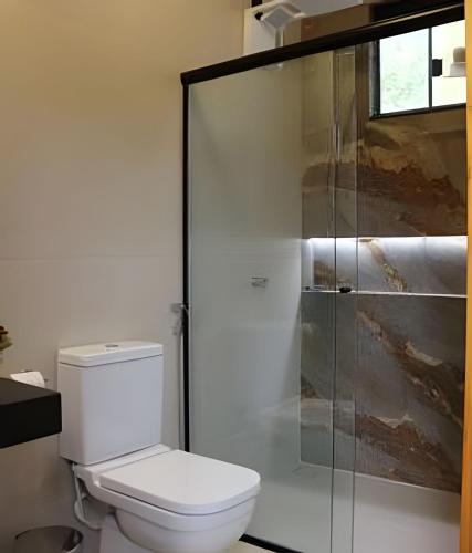 a bathroom with a toilet and a glass shower at Studio Hebron: Refúgio Entre a Cidade e a Natureza in Anápolis