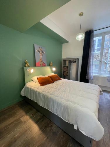 a bedroom with a bed with white sheets and orange pillows at Le balcon du Beffroi in Fougères