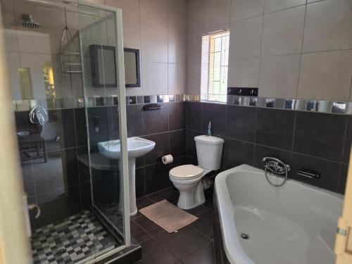 a bathroom with a toilet and a shower and a sink at Sekelbos Guesthouse in Pretoria