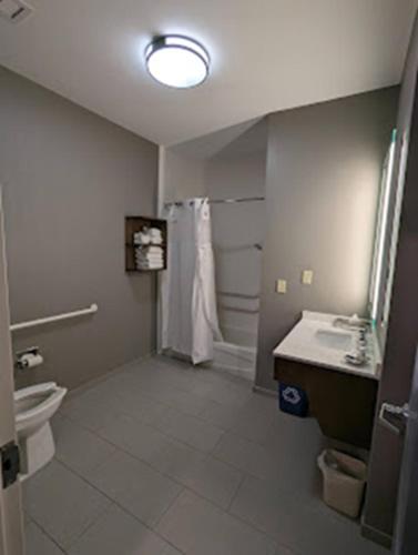 a bathroom with a toilet and a sink and a shower at Staybridge Suites Rogers - Bentonville by IHG in Rogers
