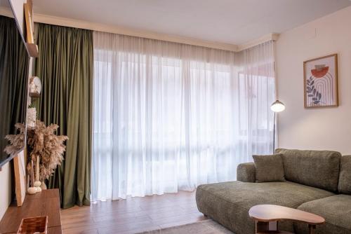 a living room with a couch and a large window at Forestline Apartment Sinaia in Sinaia