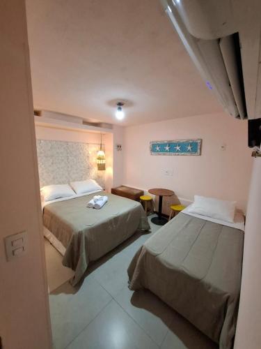 a hotel room with two beds and a table at Sabatico Beach House in Búzios