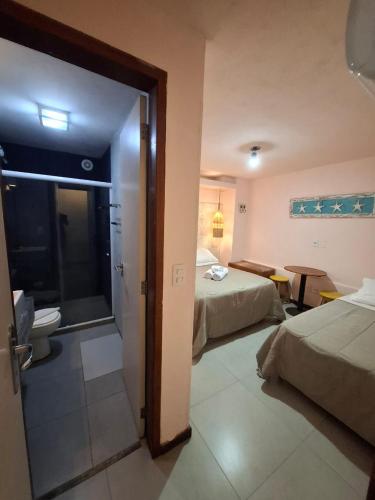 a hotel room with two beds and a bathroom at Sabatico Beach House in Búzios