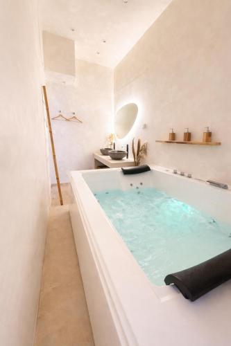 a bathtub in a white bathroom with a sink at MEEY Suite with Private Spa in Saint-Étienne