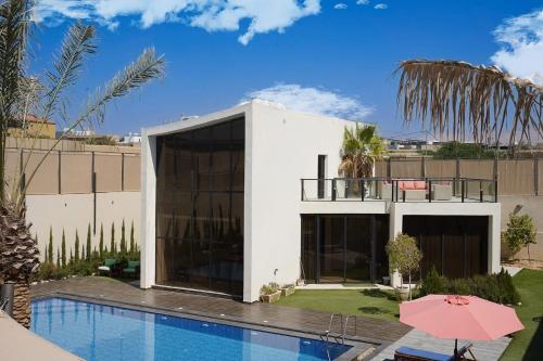 a white house with a swimming pool and a building at Atlantis The Palm Villa 2 in Al Rama