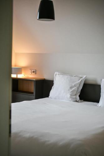 a bed with a white pillow next to a table at Les Appartements du Vignoble in Kientzheim