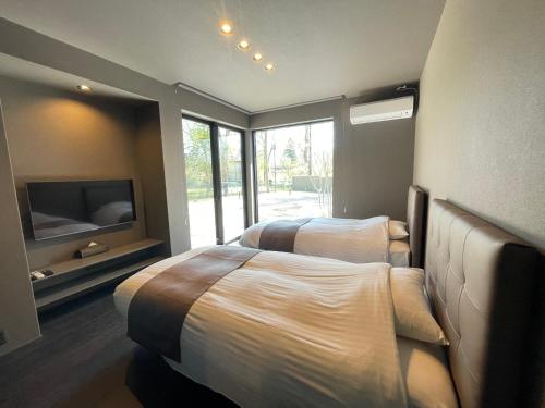a bedroom with two beds and a flat screen tv at Fuji Yamanakako Villa in Yamanakako