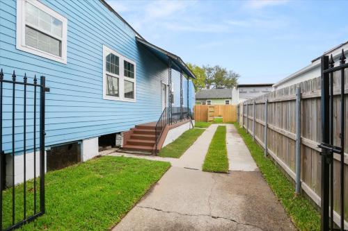 a walkway next to a blue house with a fence at Sunny 5Bed w Parking and direct Streetcar access in New Orleans