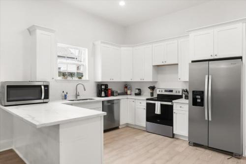 a kitchen with white cabinets and stainless steel appliances at Sunny 5Bed w Parking and direct Streetcar access in New Orleans