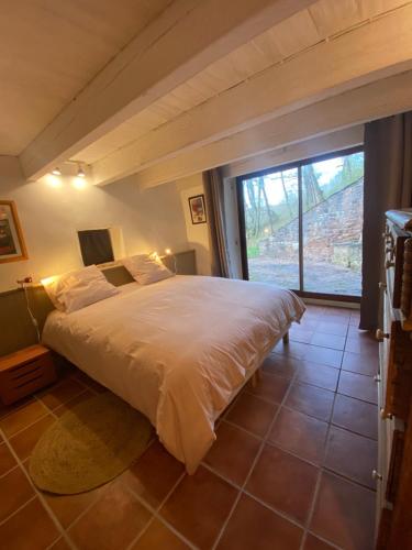 a bedroom with a large bed and a large window at La cabane de Thuriès in Camarès
