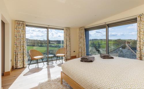 a bedroom with a bed and a large window at Rena's Retreat - Luxury Architectural Eco Home with hot tub a short walk from Gurnard in Cowes - Perfect Lux Stay for Sailers Couples and Older Families in Gurnard