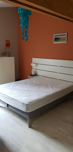a large bed in a bedroom with an orange wall at Maison des dunes in Berck-sur-Mer
