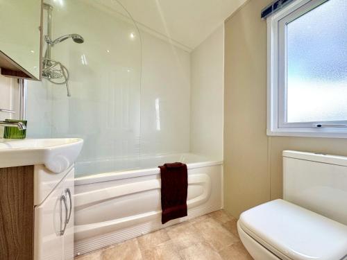 a bathroom with a tub and a toilet and a sink at Oaklands Holiday Park in Saint Osyth