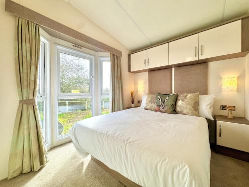 a bedroom with a large bed and a window at Oaklands Holiday Park in Saint Osyth