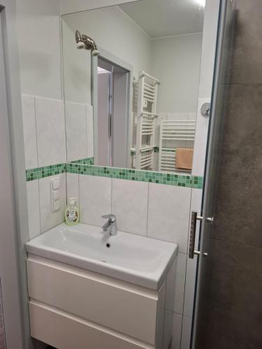 a white bathroom with a sink and a mirror at Ambrozja in Strzelin