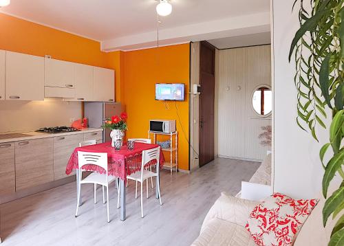 a kitchen and dining room with a red table and chairs at Appartamenti Foyer in Bibione