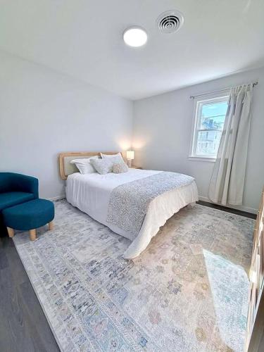 a white bedroom with a bed and a blue chair at Crewe Corner Apartment C in Crewe