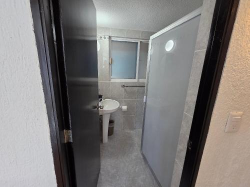 a bathroom with a shower door and a sink at Casa Secretos del Sol in Acapulco