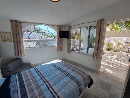 a bedroom with a bed and two large windows at Casa Secretos del Sol in Acapulco