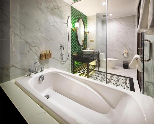 a white bath tub in a bathroom with a shower at Imperial Dalat Hotel, BW Premier Collection in Da Lat