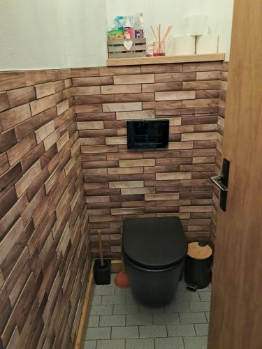 a bathroom with a toilet with a brick wall at Chambres d'hôtes chez Peggy et Eric chambre indus in Équevillon
