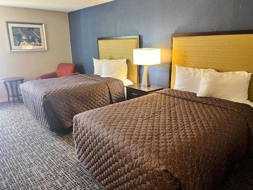 a hotel room with two beds and a lamp at UNIVERSITY INN Winston in Winston-Salem