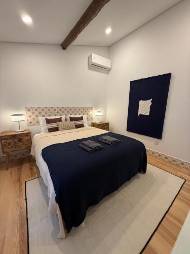 a bedroom with a large bed with a black blanket at Casa da Ana - Casinhas com Alma in Torrão
