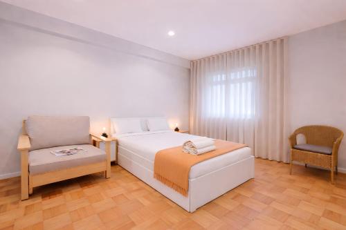 a white bedroom with a bed and a chair at FindMe InPorto Santa Catarina in Porto