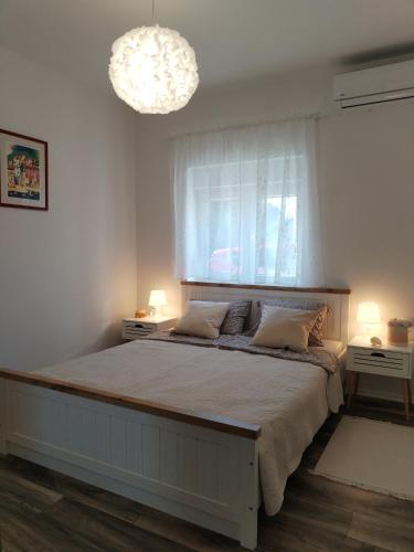 a bedroom with a bed with a window and a chandelier at Apartment Ćulum in Peračko Blato