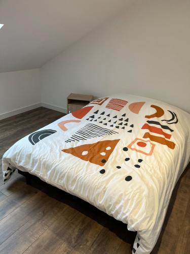 a bed with a white comforter with cats on it at Maison f3 climatisée in Montceau-les-Mines