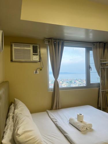 a bedroom with a window and a bed with towels at Avida Tower 2 in Davao City