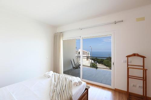 a bedroom with a bed and a large sliding glass door at T3-Sitio do Surf in Nazaré