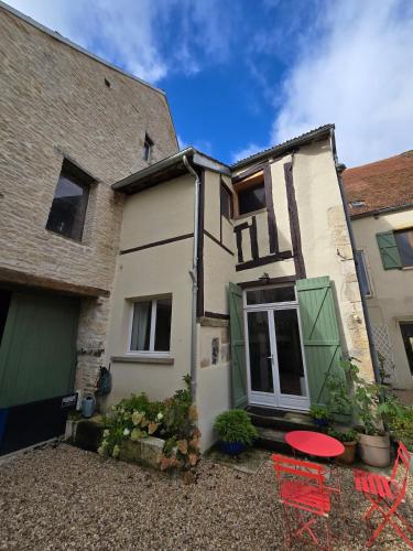 a house with two red chairs in front of it at The Little Hideaway - La Petite Maison Cachée in Noyers