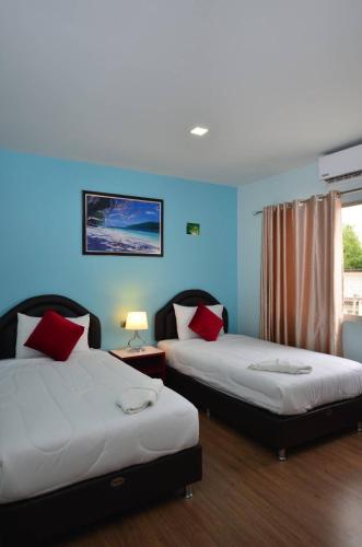 two beds in a room with blue walls at โรงแรมสตูลธานี satun tanee hotel in Satun