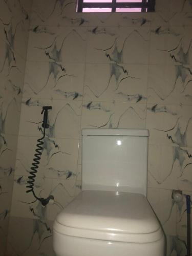 a white toilet in a bathroom with a stone wall at The 7th Haven in Uyo