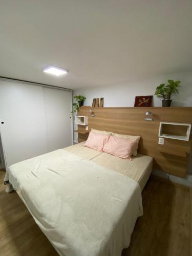a bedroom with a large white bed with pink pillows at Refúgio Subterrâneo in Genuino Sampaio