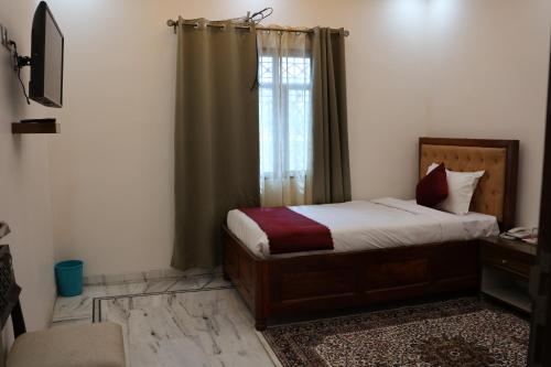 a small bedroom with a bed and a window at Nice View Hotel in Gopālganj