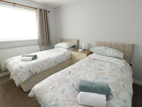 a bedroom with two beds and a window at Min Y Cae in Cemaes Bay