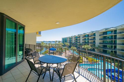 a balcony with a table and chairs and a swimming pool at Phoenix on the Bay 1326 condo in Orange Beach