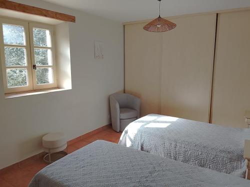 a bedroom with two beds and a chair and a window at La Maison du Bonheur in Jaujac