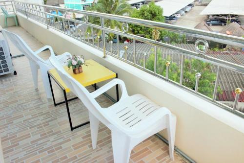 two white chairs and a yellow table on a balcony at Uncle House Krabi in Krabi town