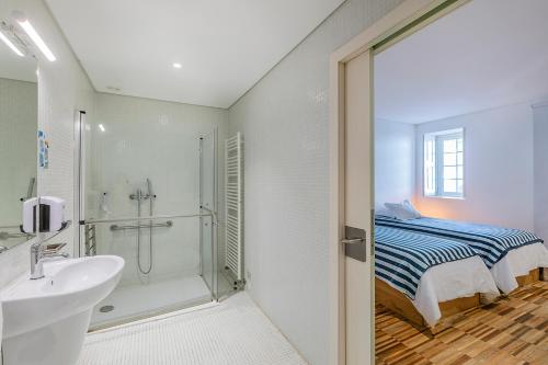 a bathroom with a sink and a shower and a bed at HI Vila do Conde - Pousada de Juventude in Vila do Conde