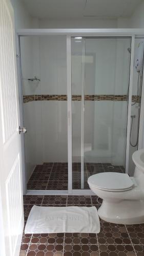 uma casa de banho com uma cabina de duche em vidro e um WC. em Charoensuk Grand Hotel em Kabin Buri